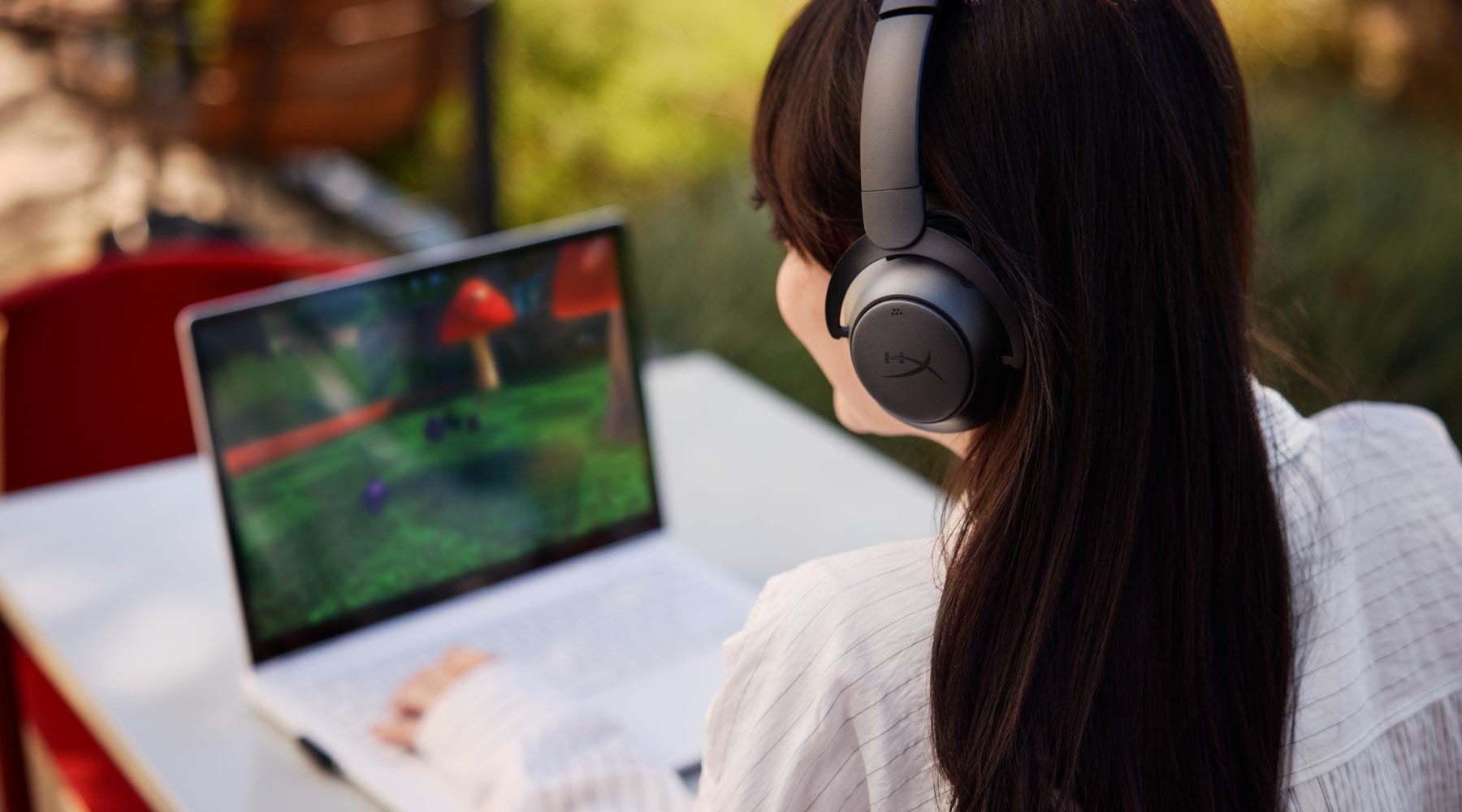Person playing a video game on an OMEN laptop while wearing Cloud MIX 2 headphones