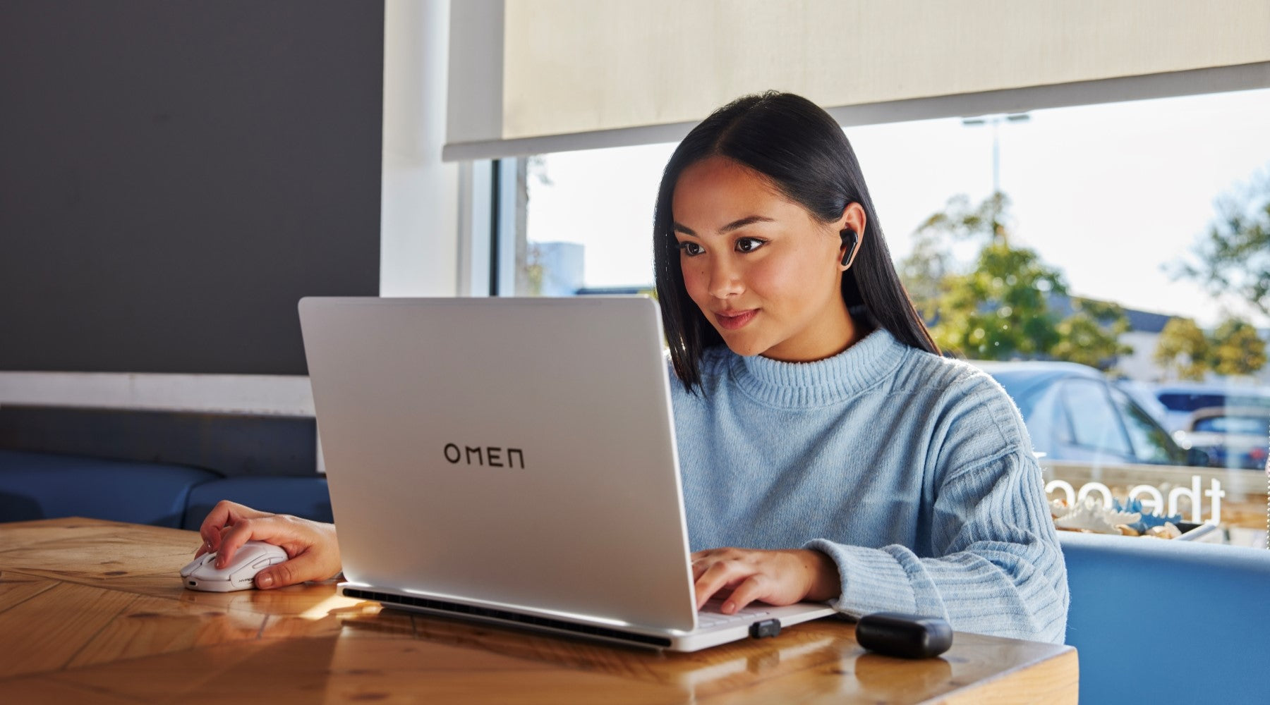 Person working on an OMEN laptop while wearing the Cloud Mix Buds 2 earbuds